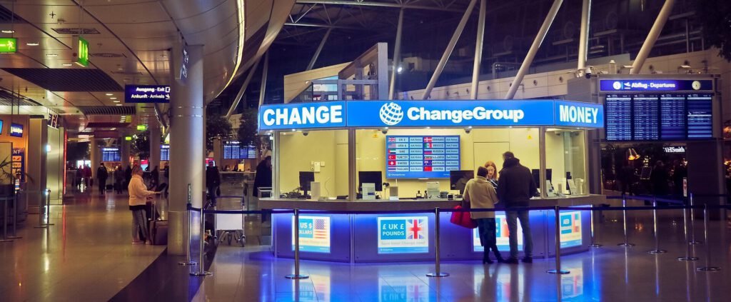 공항 터미널 내부에 위치한 파란색 체인지그룹 환전소 창구 앞에서 여행객들이 외화를 환전하고 있는 모습